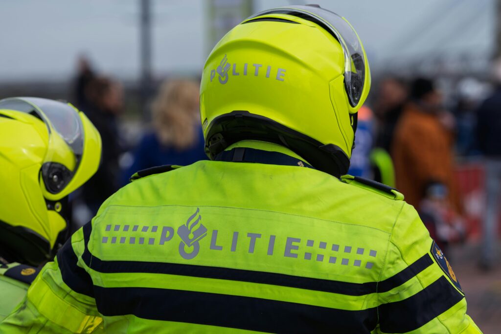 Dutch police officers in high-visibility jackets and helmets at an outdoor event.