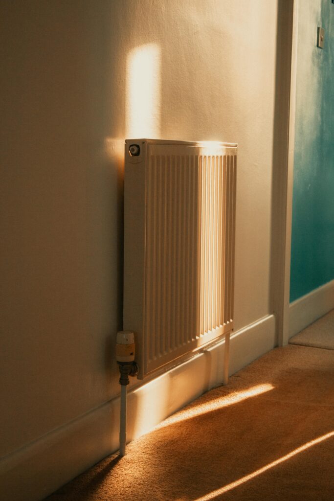 A wall-mounted radiator warmly lit by sunlight in a cozy indoor setting.