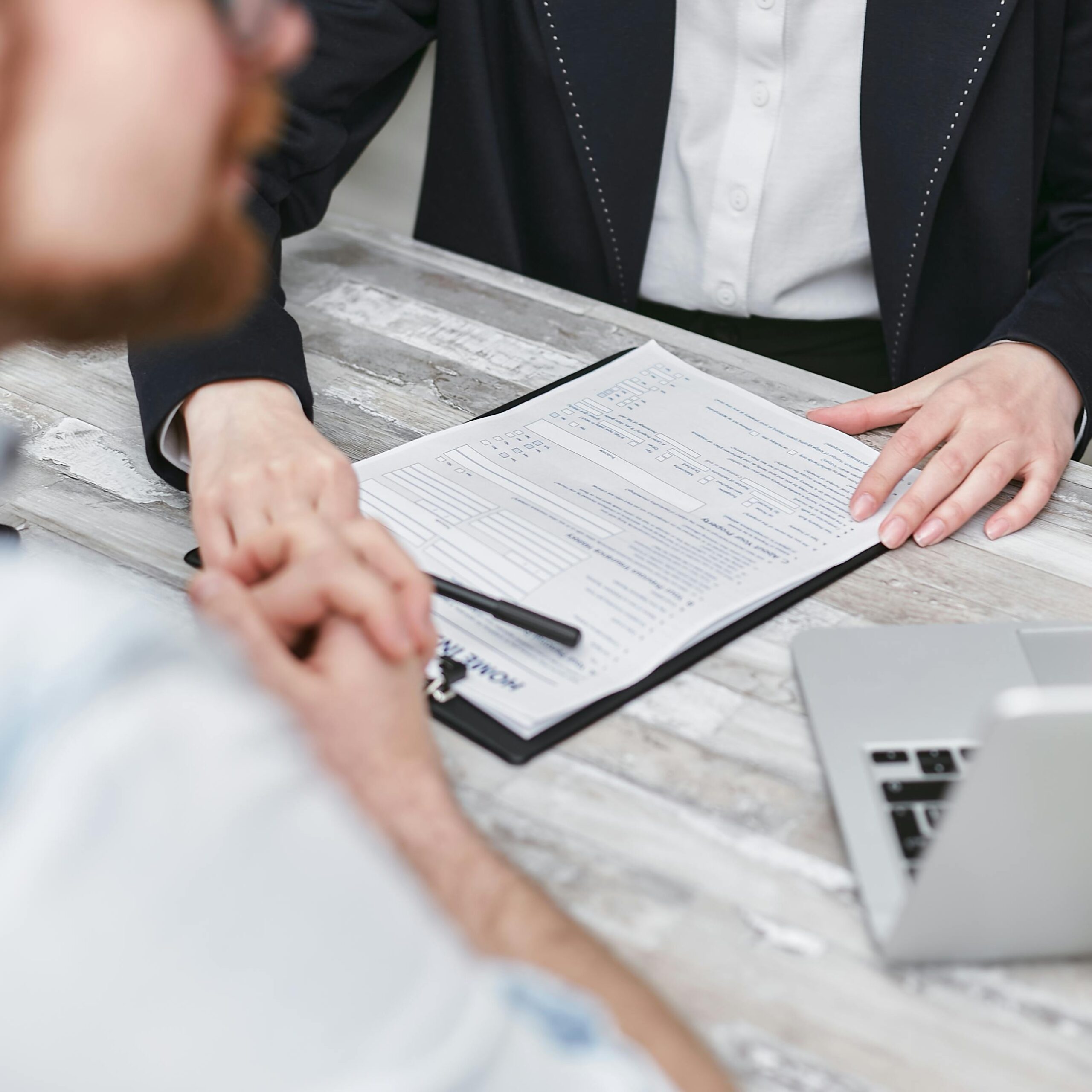 Two people in a business meeting reviewing documents on a clipboard.