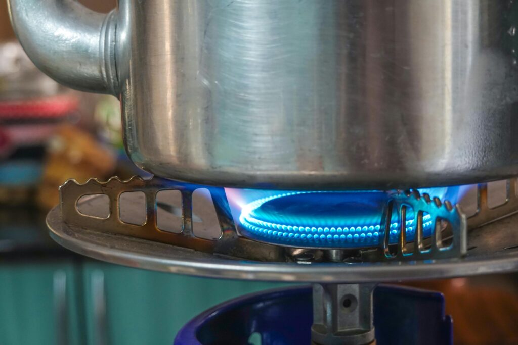 A detailed image showing a gas stove burner with a pot above, highlighting kitchen heat and flame.