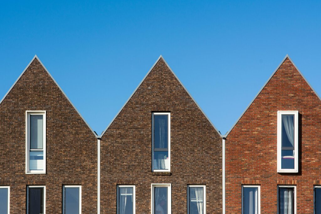 Contemporary brick houses with triangular roofs stand tall under a vivid blue sky.